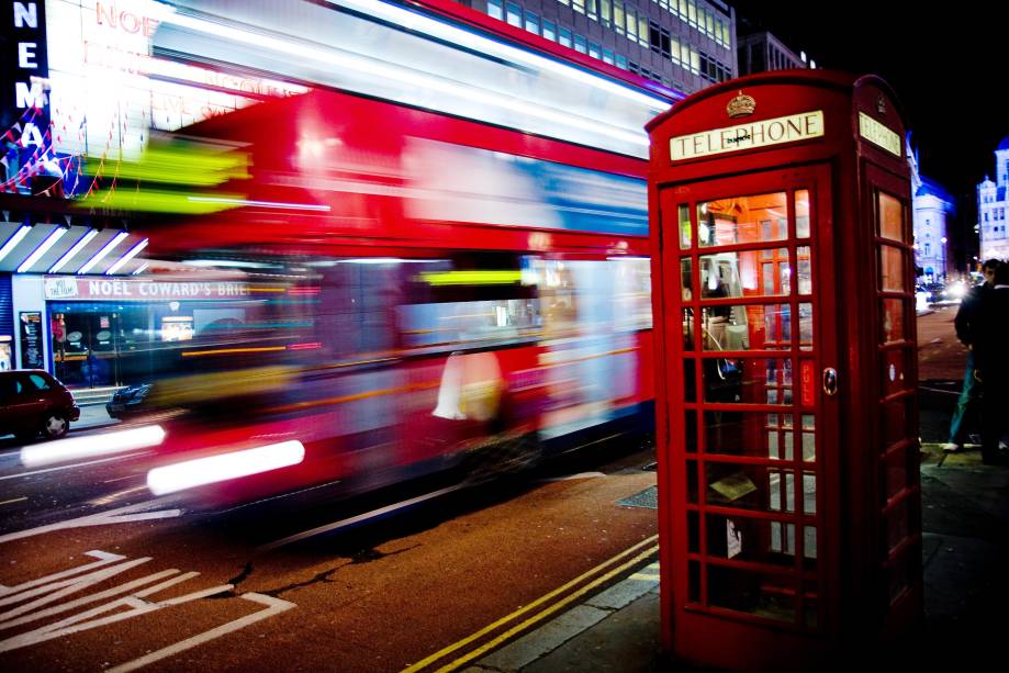 O lendário Routemaster, um ônibus vermelho de dois andares, passa por trás de outro marco de Londres: as cabines telefônicas vermelhas!
