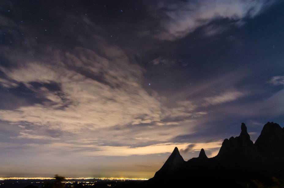 Vista noturna de Teresópolis com a silhueta de seu ponto turístico mais famoso: o Dedo de Deus